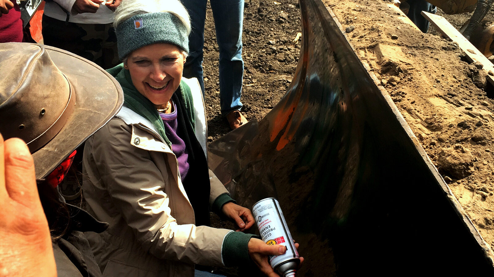 In this Tuesday, Sept. 6, 2016 photo, Green Party presidential candidate Jill Stein prepares to spray-paint "I approve this message" in red paint on the blade of a bulldozer at a protest against the Dakota Access Pipeline in the area of Morton County, N.D. Morton County Sheriff Kyle Kirchmeier said Tuesday that authorities plan to pursue charges against Stein.