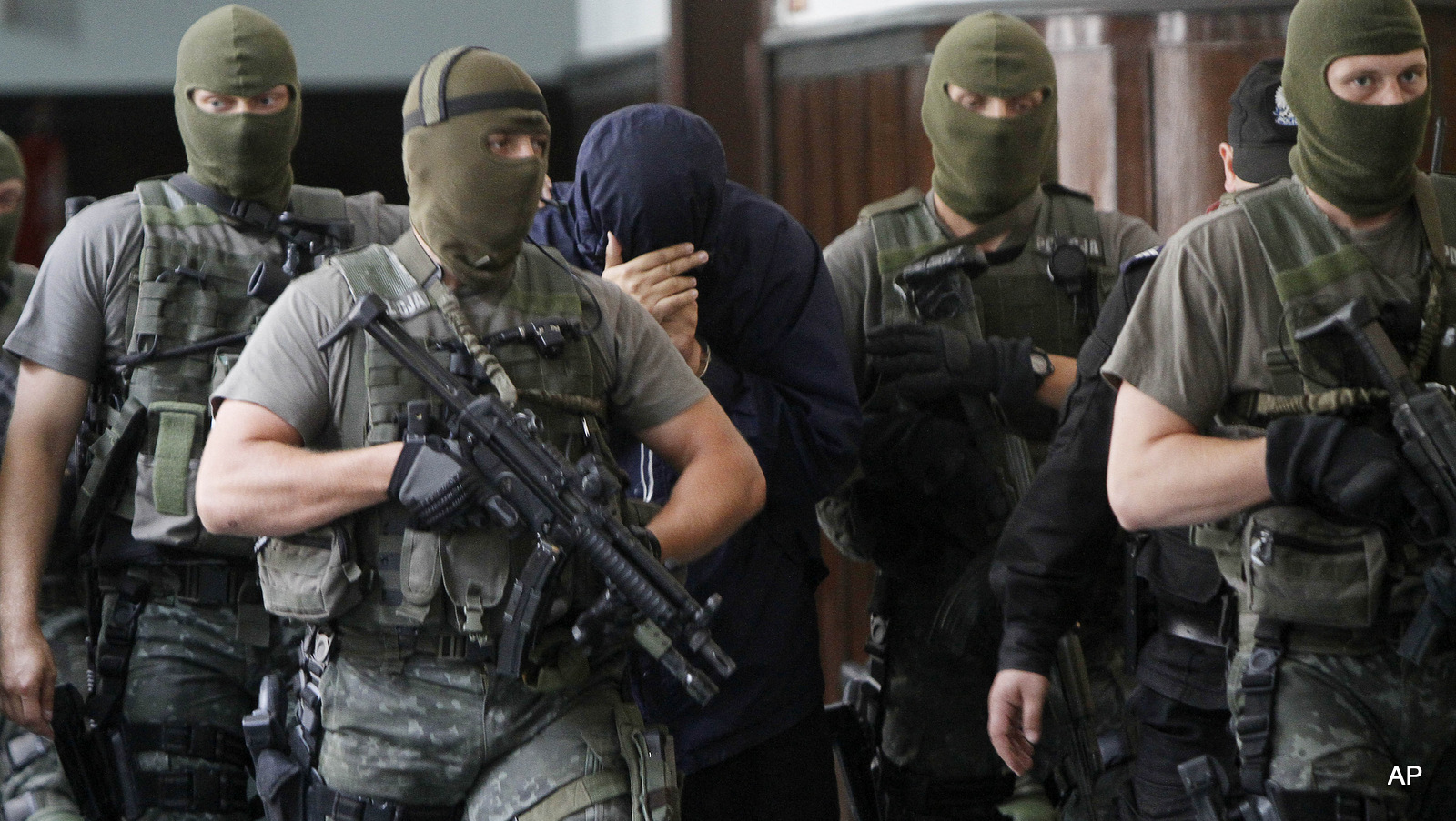 Israeli citizen Uri Brodsky, center, covers his face as he is escorted by anti-terrorist force members into court in Warsaw, Poland, on Wednesday, July 7, 2010, where he was ordered to be extradited to Germany, suspected of being a Mossad agent involved in the slaying of an alleged Hamas operative. 
