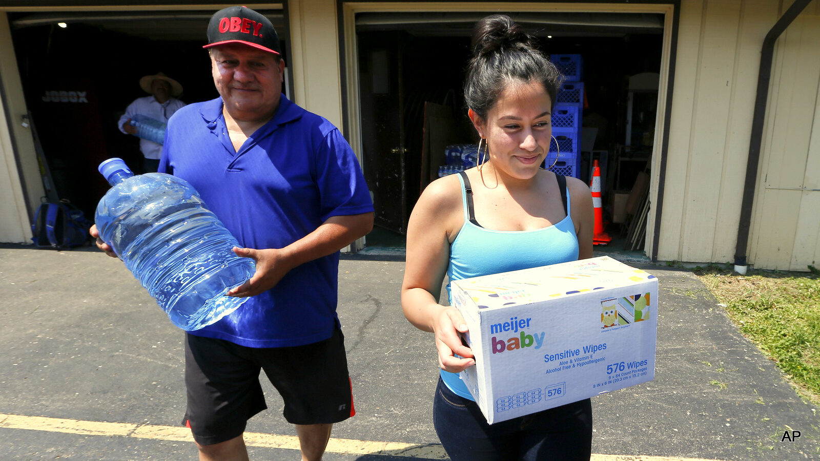 Margarita Solis, carries wipes as Rick Vasquez carries bottled water at Out Lady of Guadalupe Church in Flint, Mich. Solis regularly drives to Flint distribution centers to load up on bottled water, as thousands of residents have done in the city coping with a contaminated water crisis.