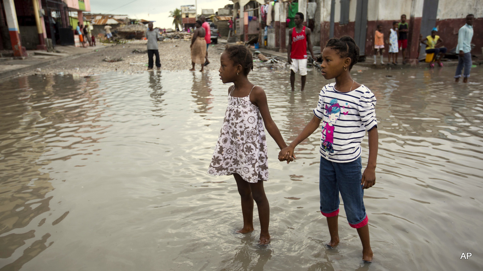 Girls hold hands as they help each other wade through a flooded street after the passing of Hurricane Matthew in Les Cayes, Haiti, Thursday, Oct. 6, 2016. Two days after the storm rampaged across the country's remote southwestern peninsula, authorities and aid workers still lack a clear picture of what they fear is the country's biggest disaster in years.