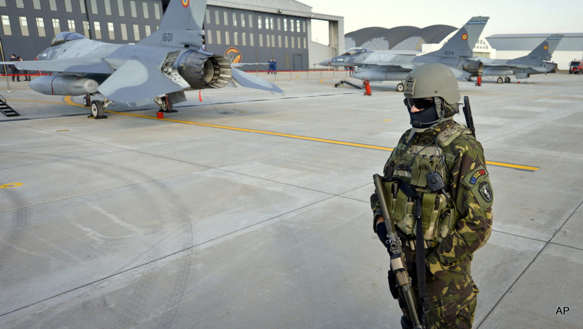 A Romanian soldier secures the perimeter around Romanian Air Force F16 fighter jets parked on the runway of the Air Base 86, in Borcea, southern Romania, Friday, Oct. 7, 2016. The air force staged an event to mark the entry into service of the first six US made aircraft, purchased from Portugal's military, as part of the process to replace the country's Russian made MIG 21 fleet.