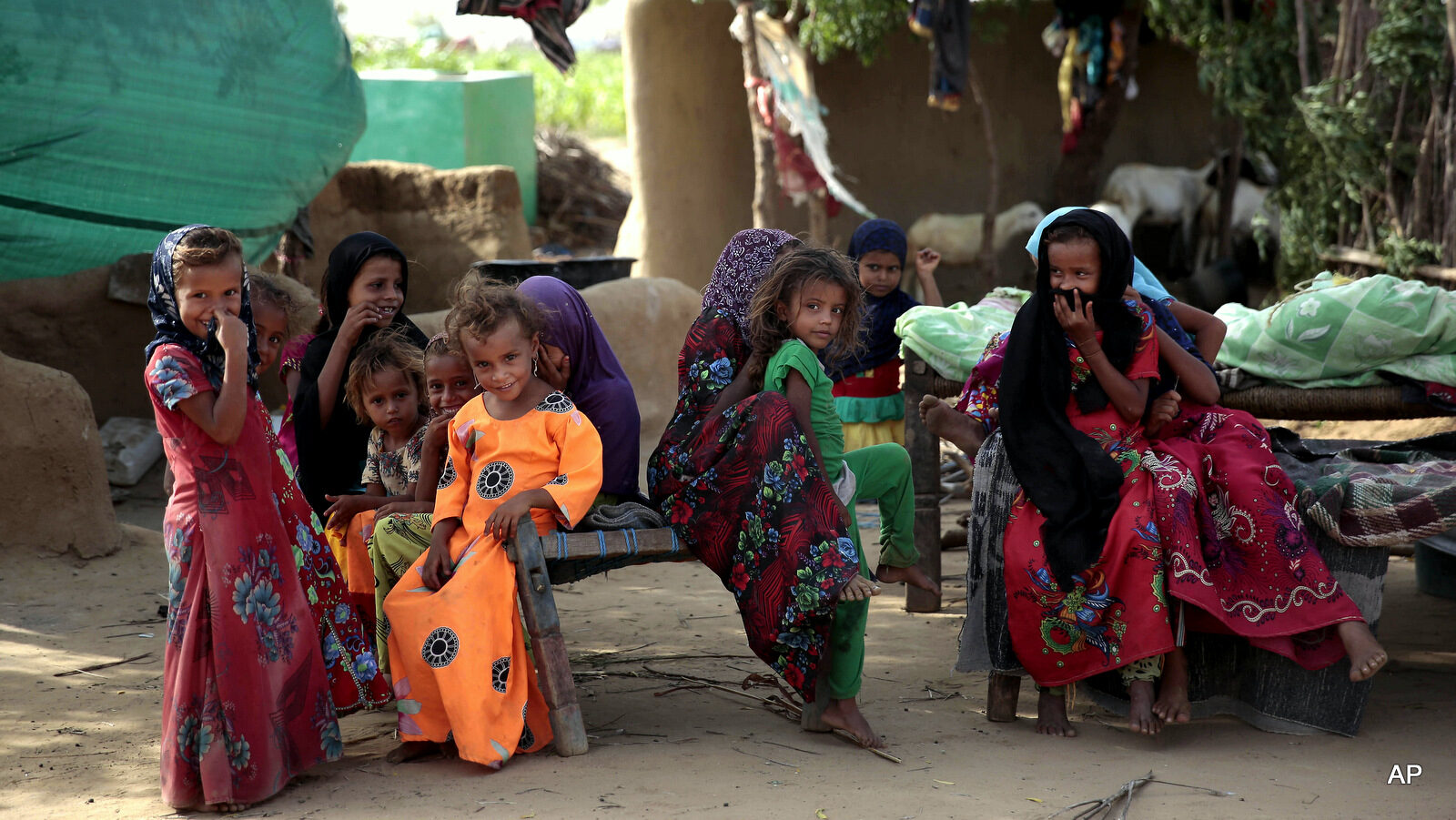 In this photo taken on Friday, Oct. 7, 2016, girls gather at a camp for internally displaced people near the town of Abs, located on Yemen’s western coastal plain below towering desert mountains. Hundreds of Yemenis fleeing war are now living in tents and mud-brick shelters scattered across a cornfield, where they buried the remains of loved ones they carried with them when they escaped.