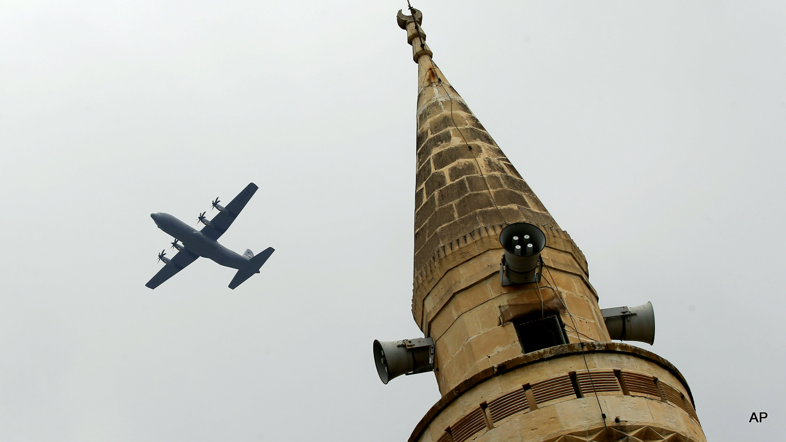 With a mosque's minaret in the foreground, a United States Air Force cargo plane takes off from the Incirlik Air Base in southern Turkey, where coalition forces launch attacks inside of Syria, July 30, 2015.