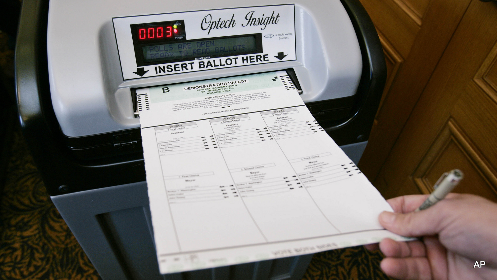 A sales executive with Sequoia Voting Systems demonstrates inserting a ballot into their electronic voting system for officials in San Francisco, Dec. 5, 2007