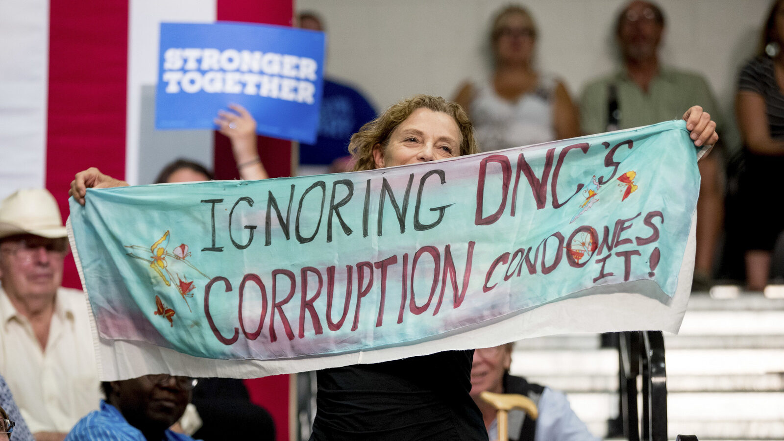 A woman in the audience hold up fabric that reads "Ignoring DNC's Corruption Condones It!" as Democratic presidential candidate Hillary Clinton speaks at a rally at Adams City High School in Commerce City, Colo., Wednesday, Aug. 3, 2016. (AP Photo/Andrew Harnik)