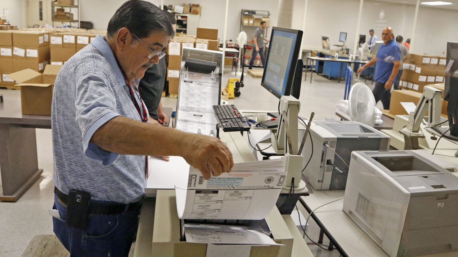 An Arizona elections official at the Maricopa inserts ballots into a machine to recount the votes in the 5th Congressional District race Tuesday, Sept. 13, 2016, in Phoenix. (AP Photo/Ross D. Franklin)