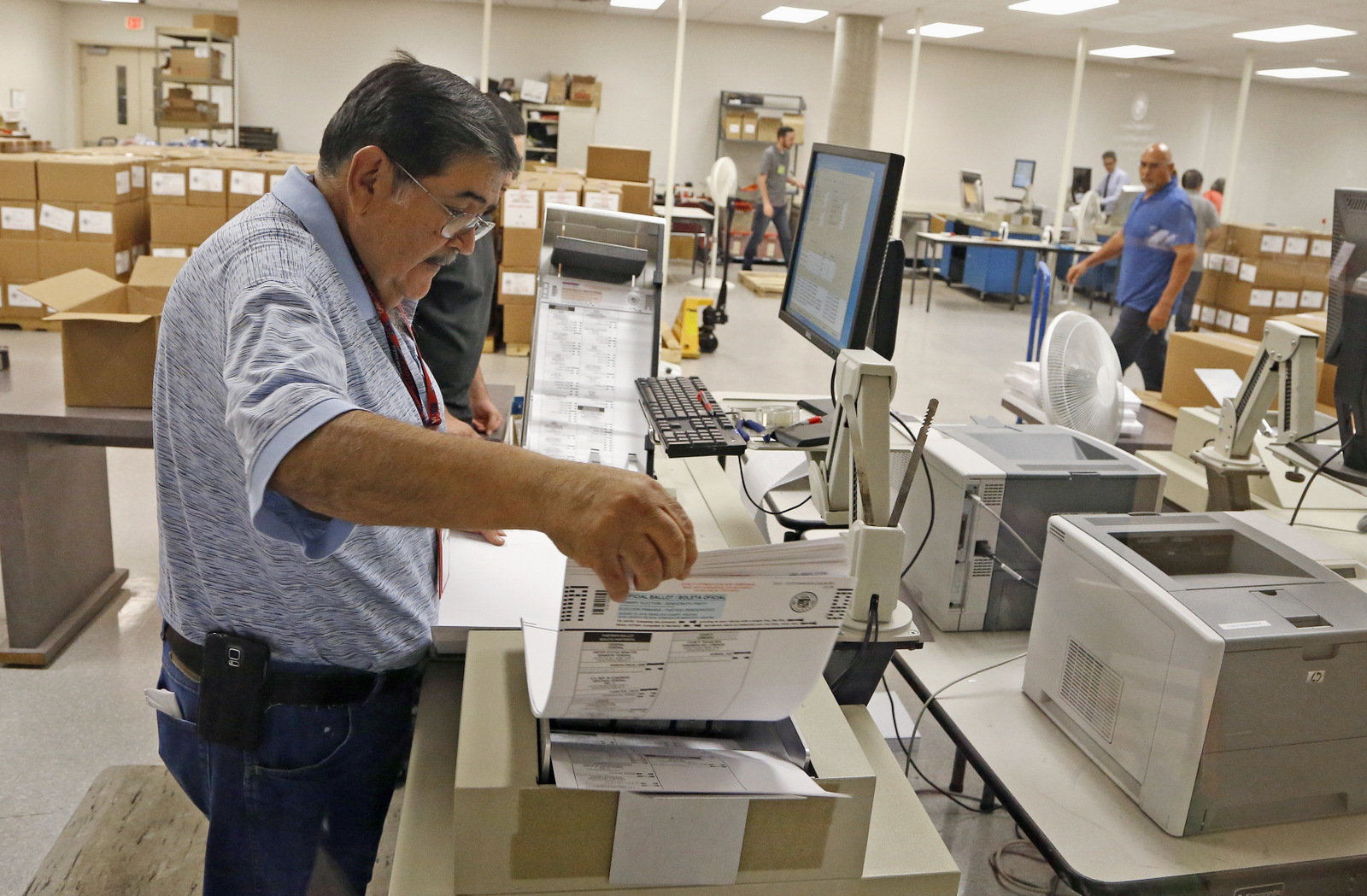An Arizona elections official at the Maricopa inserts ballots into a machine to recount the votes in the 5th Congressional District race Tuesday, Sept. 13, 2016, in Phoenix. (AP Photo/Ross D. Franklin)