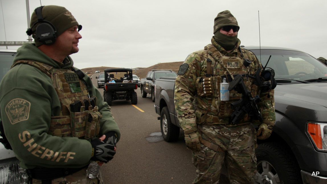 Two members of the Stutsman County SWAT team talk while deployed to watch protesters demonstrating against the Dakota Access Pipeline encroaching the water source near the Stand Rock Sioux Reservation, as they stand next to a police barricade on Highway 1806 in Cannon Ball, N.D., Sunday, Oct. 30, 2016.