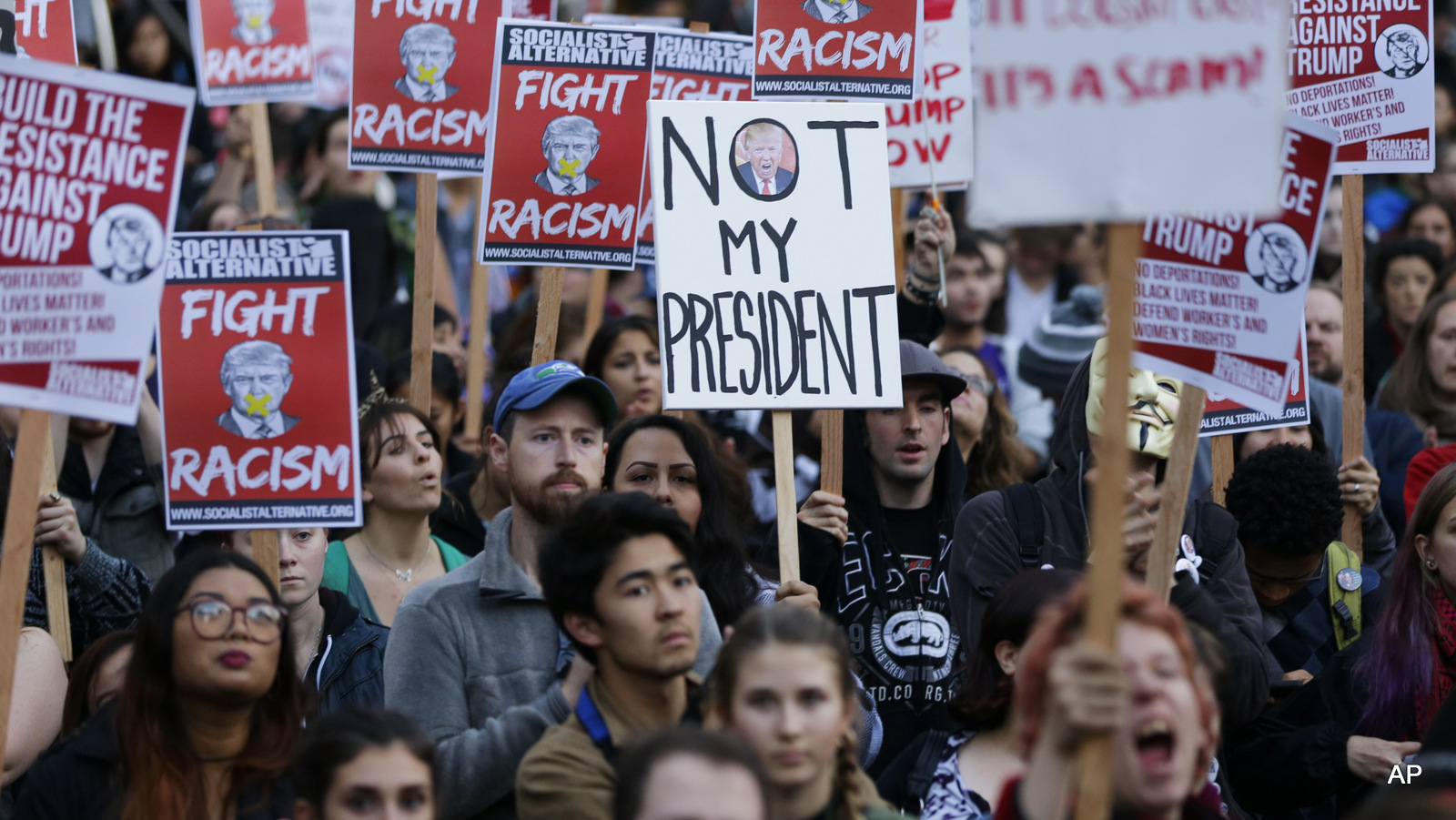 Protesters hold signs during a protest against the election of President-elect Donald Trump, Wednesday, Nov. 9, 2016, in downtown Seattle.