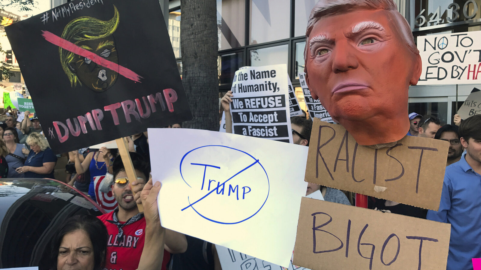 Protesters hold banners during a rally outside the CNN studios, in opposition to President-elect Donald Trump, in the Hollywood section of Los Angeles on Sunday, Nov .13, 2016. (AP Photo/Damian Dovarganes)