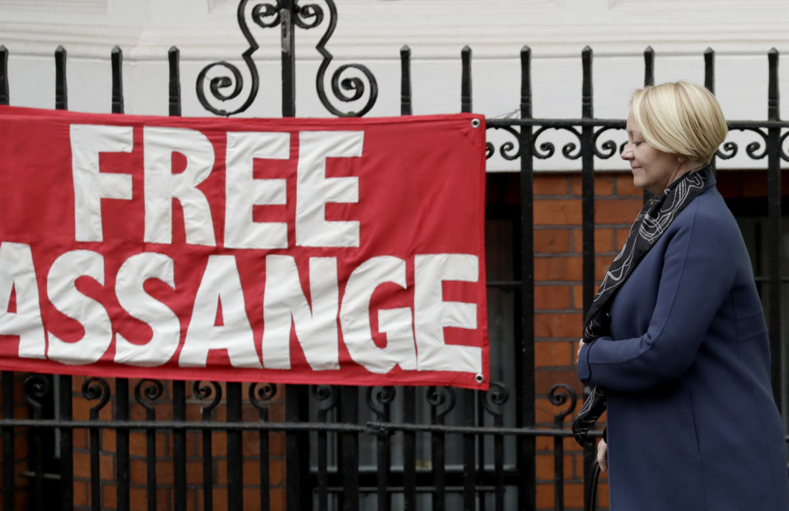 Swedish prosecutor Ingrid Isgren passes a banner put up by a supporter of Wikileaks founder Julian Assange as she walks to a vehicle, on the second day at the Ecuadorian embassy in London, Tuesday, Nov. 15, 2016. Isgren went to the embassy Monday and Tuesday to question Wikileaks founder Julian Assange about allegations concerning possible sexual misconduct committed in Sweden six years ago. (AP Photo/Matt Dunham)