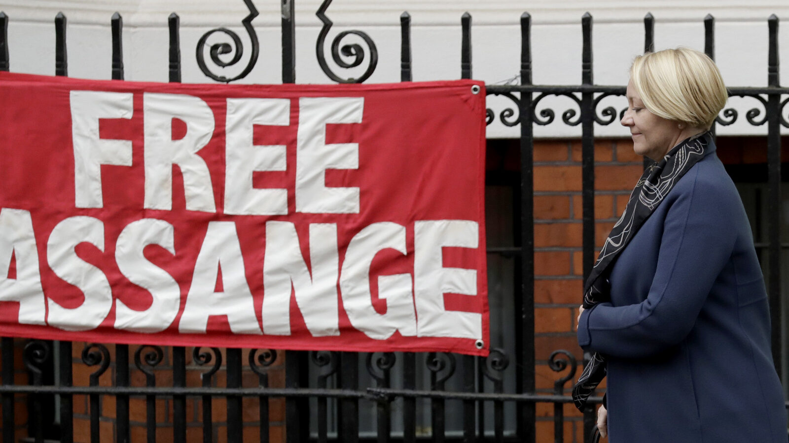 Swedish prosecutor Ingrid Isgren passes a banner put up by a supporter of Wikileaks founder Julian Assange as she walks to a vehicle, on the second day at the Ecuadorian embassy in London, Tuesday, Nov. 15, 2016. Isgren went to the embassy Monday and Tuesday to question Wikileaks founder Julian Assange about allegations concerning possible sexual misconduct committed in Sweden six years ago. (AP Photo/Matt Dunham)