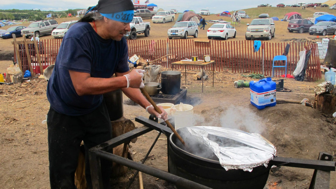 Phil Daw Sr., of Albuquerque, New Mexico, helps cook beef stew to feed hundreds at an encampment near North Dakota's Standing Rock Sioux reservation. (AP Photo/James MacPherson)