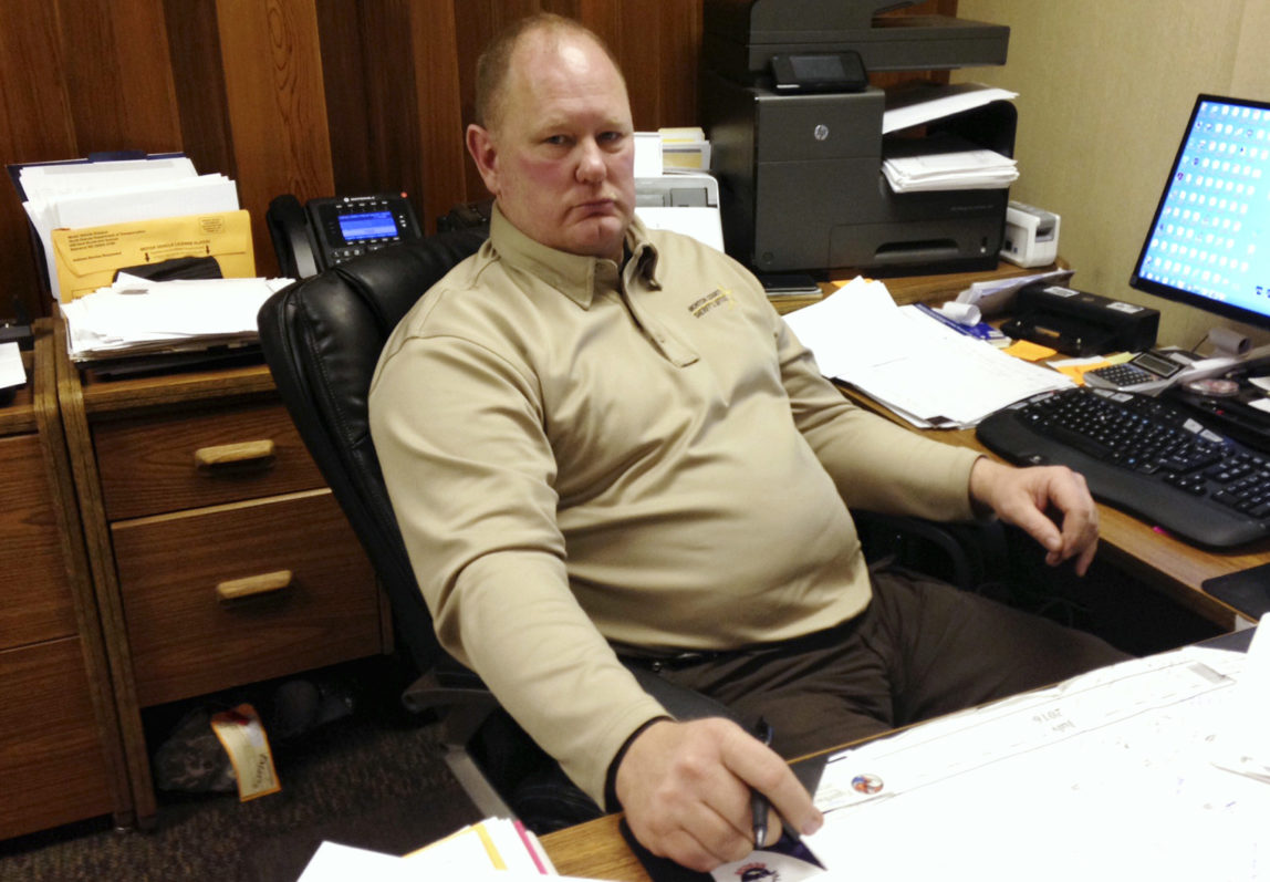 In this Tuesday, photo, Morton County Sheriff Kyle Kirchmeier looks up from his desk in Mandan, N.D. Kirchmeier has led the police response to the Dakota Access oil pipeline protests, and shrugs off criticism that that response has been heavy-handed at times. Nov. 22, 2016 (AP Photo/James MacPherson)