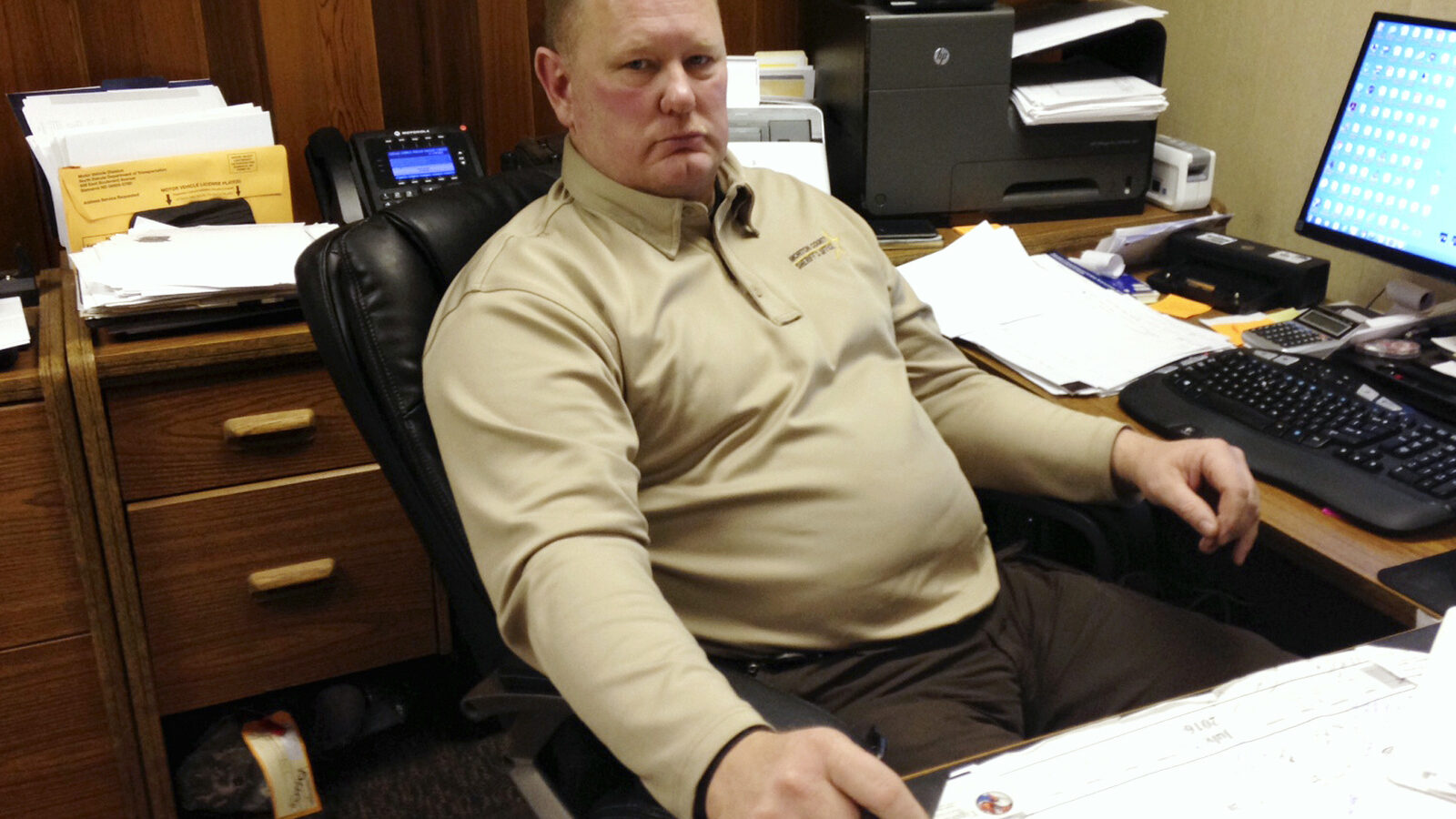 In this Tuesday, photo, Morton County Sheriff Kyle Kirchmeier looks up from his desk in Mandan, N.D. Kirchmeier has led the police response to the Dakota Access oil pipeline protests, and shrugs off criticism that that response has been heavy-handed at times. Nov. 22, 2016 (AP Photo/James MacPherson)