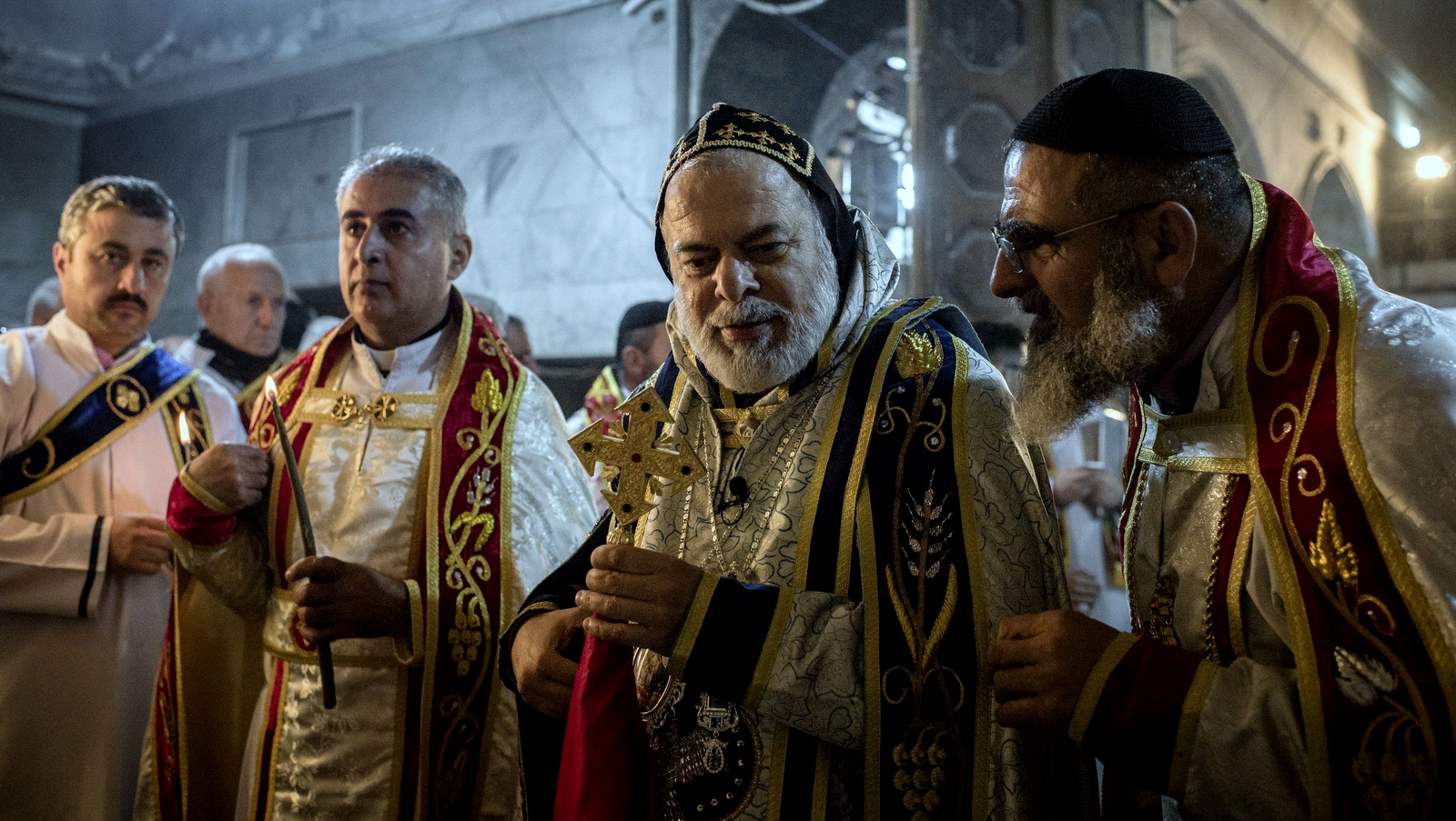 Priests lead a Christmas Eve's Mass in the Assyrian Orthodox church of Mart Shmoni, in Bartella, Iraq, Saturday, December 24, 2016. For the 300 Christians who braved rain and wind to attend the mass in their hometown, the ceremony provided them with as much holiday cheer as grim reminders of the war still raging on around their northern Iraqi town and the distant prospect of moving back home. Displaced when the Islamic State seized their town in 2014, they were bused into the town from Irbil, capital of the self-ruled Kurdish region, where they have lived for more than two years. (AP Photo/Cengiz Yar)