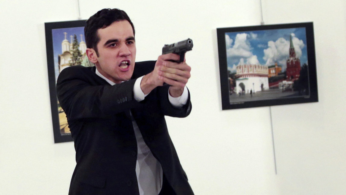 ADDS THE NAME OF THE GUNMAN - A man identified as Mevlut Mert Altintas holds up a gun after shooting Andrei Karlov, the Russian Ambassador to Turkey, at a photo gallery in Ankara, Turkey, Monday, Dec. 19, 2016. (AP/Burhan Ozbilici)