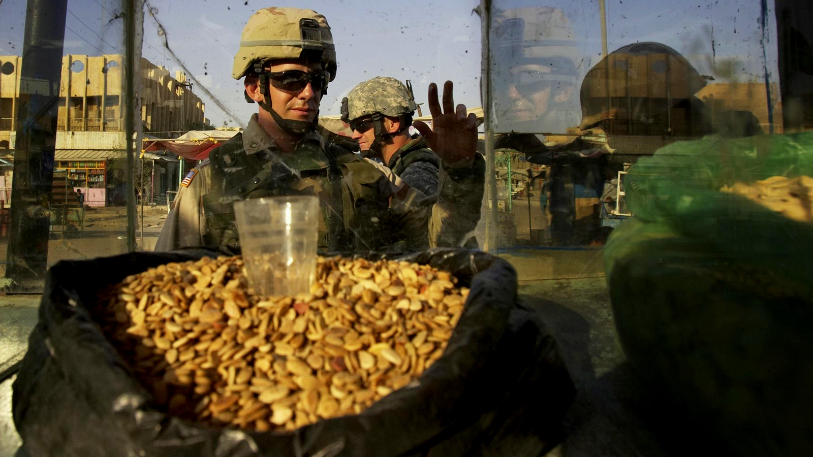 A U.S. Army soldier walks passed a seed vendor in Sadr City in Baghdad, Iraq, July 28, 2005. (AP Photo/Jacob Silberberg)