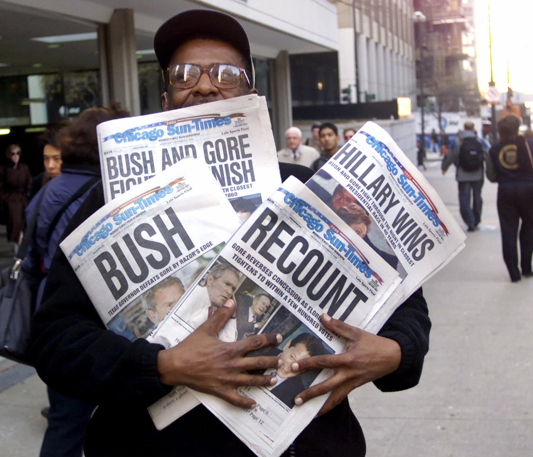 FILE - In this Nov. 8, 2000 file photo, Willie Smith holds four copies of the Chicago Sun-Times, each with a different headline, in Chicago, reflecting a night of suspense, drama and changes in following the presidential race between Vice President Al Gore and Texas Gov. George W. Bush. What happens if America wakes up on Nov. 9 to a disputed presidential election in which the outcome turns on the results of a razor-thin margin in one or two states, one candidate seeks a recount and the other goes to court? (AP Photo/Charles Bennett, File)