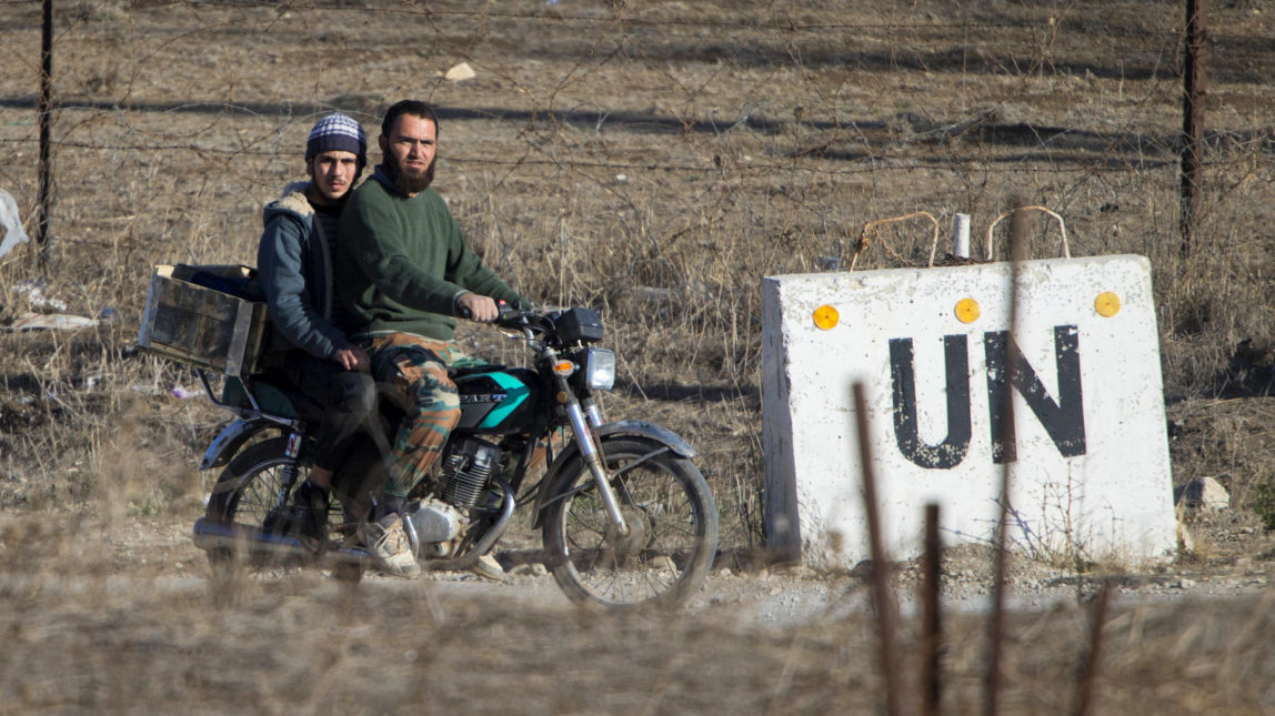Two men, not specified which group of rebels, ride a motorcycle towards an abandoned UN base at Syria's Quneitra border crossing between Syria and the Israeli-controlled Golan Heights, Monday, Nov. 28, 2016. (AP Photo/Ariel Schalit)