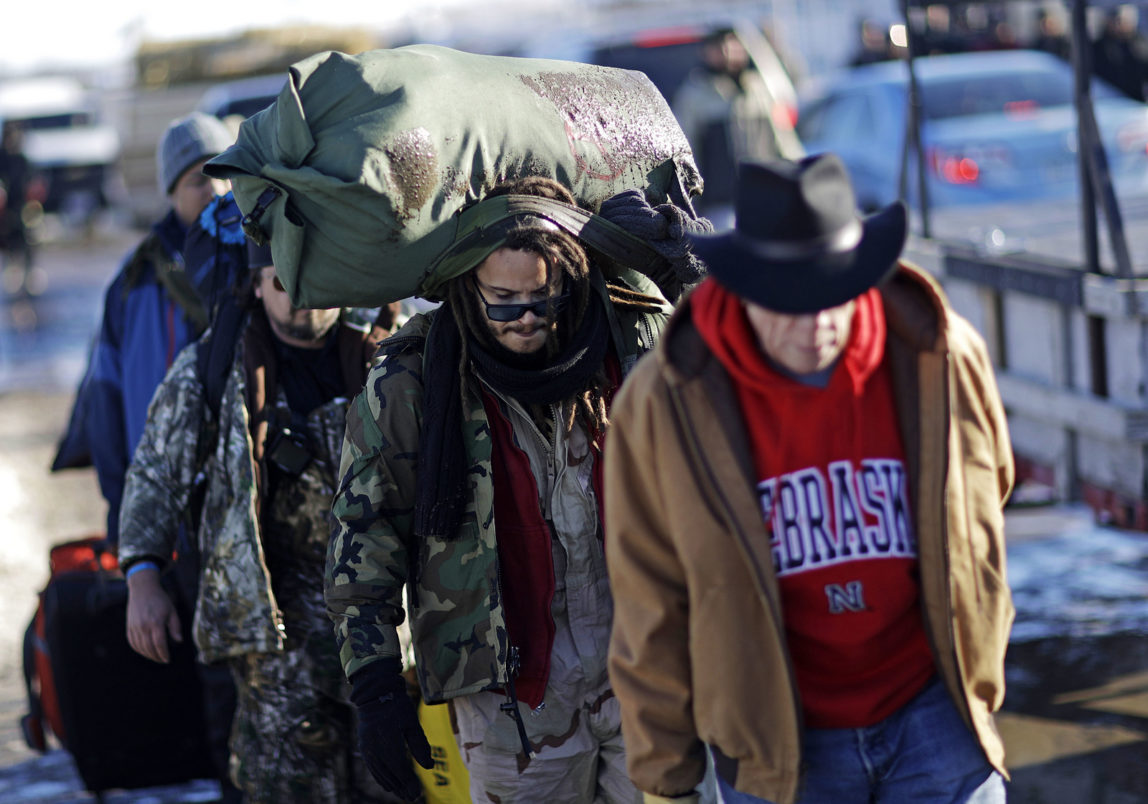 Marine Corps veteran Nesky Hernandez, center, carries his pack after arriving with fellow veterans at the Oceti Sakowin camp where people have gathered to protest the Dakota Access oil pipeline in Cannon Ball, N.D., Sunday, Dec. 4, 2016. Tribal elders have asked the military veterans joining the large Dakota Access pipeline protest encampment not to have confrontations with law enforcement officials, an organizer with Veterans Stand for Standing Rock said Sunday, adding the group is there to help out those who've dug in against the four-state, $3.8 billion project. (AP Photo/David Goldman)