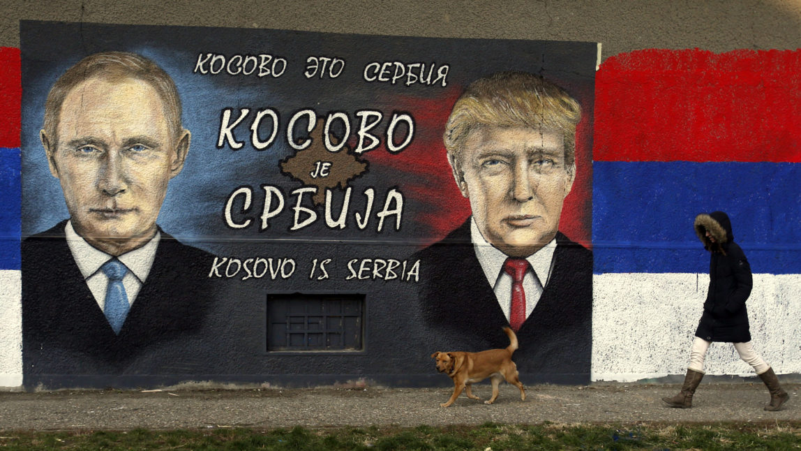 A woman passes by graffiti depicting the Russian President Vladimir Putin, left, and US President Elect Donald Trump in a suburb of Belgrade, Serbia, Tuesday, Dec. 6, 2016. The Cyrillic letters on graffiti read "Kosovo is Serbia", as Serbia doesn't recognise Kosovo's independence. (AP Photo/Darko Vojinovic)