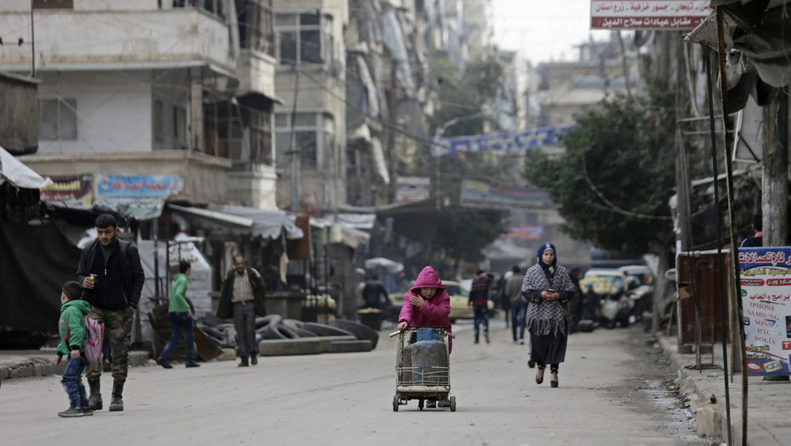 In this Monday, Dec. 5, 2016 photo, a Syrian girl pushes a cart loaded with cooking gas canisters, in Aleppo, Syria. A rebel defeat in Aleppo, Syria’s largest city and former commercial center, is likely to reverberate across the war-torn country, where opposition forces continue to hold out in smaller, more disconnected areas. (AP Photo/Hassan Ammar)