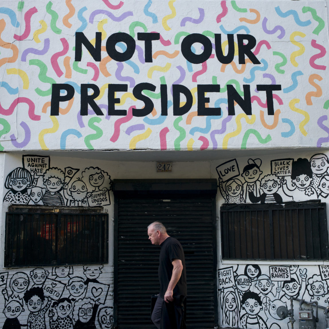 A man walks past a building with the phrase "Not Our President" written on the facade to protest against President-elect Donald Trump Thursday, Dec. 8, 2016, in Los Angeles. (AP Photo/Jae C. Hong)