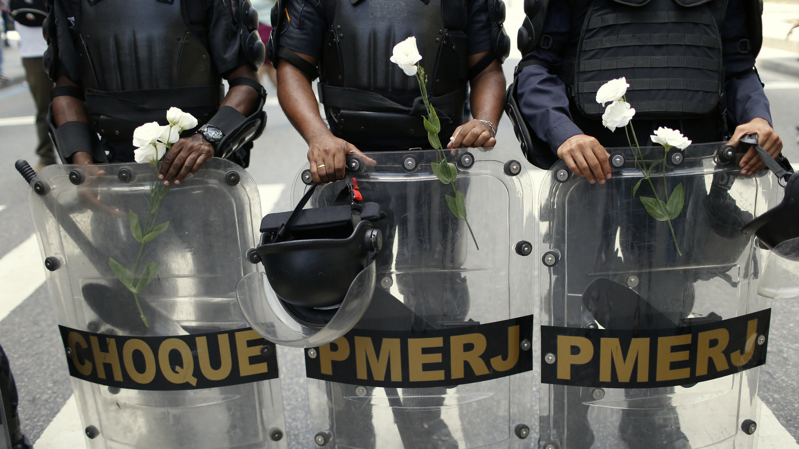 Police officers stand with flowers given to them by demonstrators during a protest against austerity measures outside the state legislature, in Rio de Janeiro, Brazil, Monday, Dec. 12, 2016. Police, firefighters and school teachers are among the workers for Brazil’s Rio de Janeiro state protesting against government austerity measures being considered by lawmakers. (AP Photo/Silvia Izquierdo)