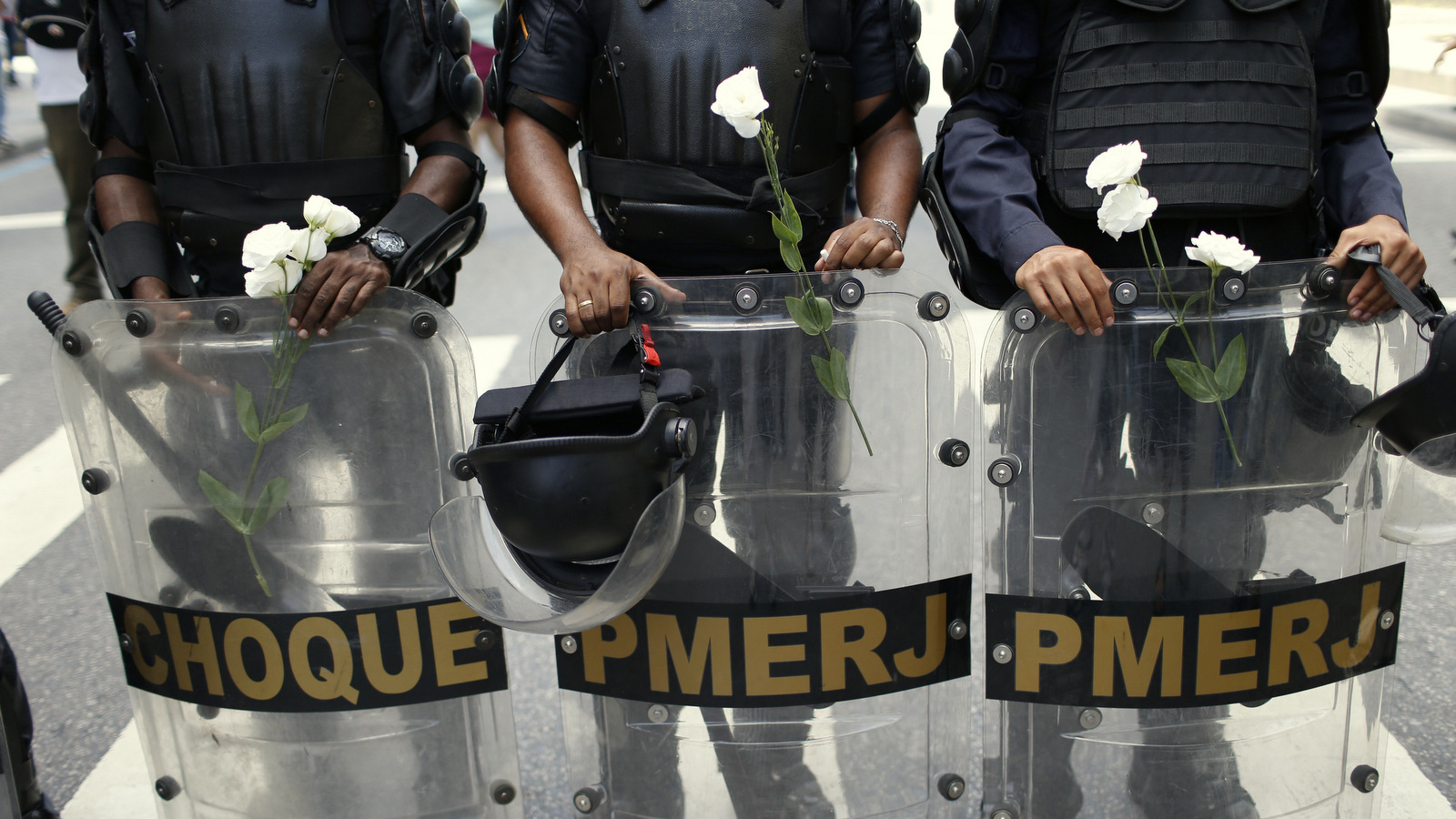 Los agentes de policía se paran con las flores que les dieron los manifestantes durante una protesta contra las medidas de austeridad fuera de la legislatura estatal, en Río de Janeiro, Brasil, el lunes 12 de diciembre de 2016. La policía, los bomberos y los maestros de escuela se encuentran entre los trabajadores del Río de Brasil. Estado de Janeiro protestando contra las medidas de austeridad del gobierno que están considerando los legisladores. (Foto AP / Silvia Izquierdo)