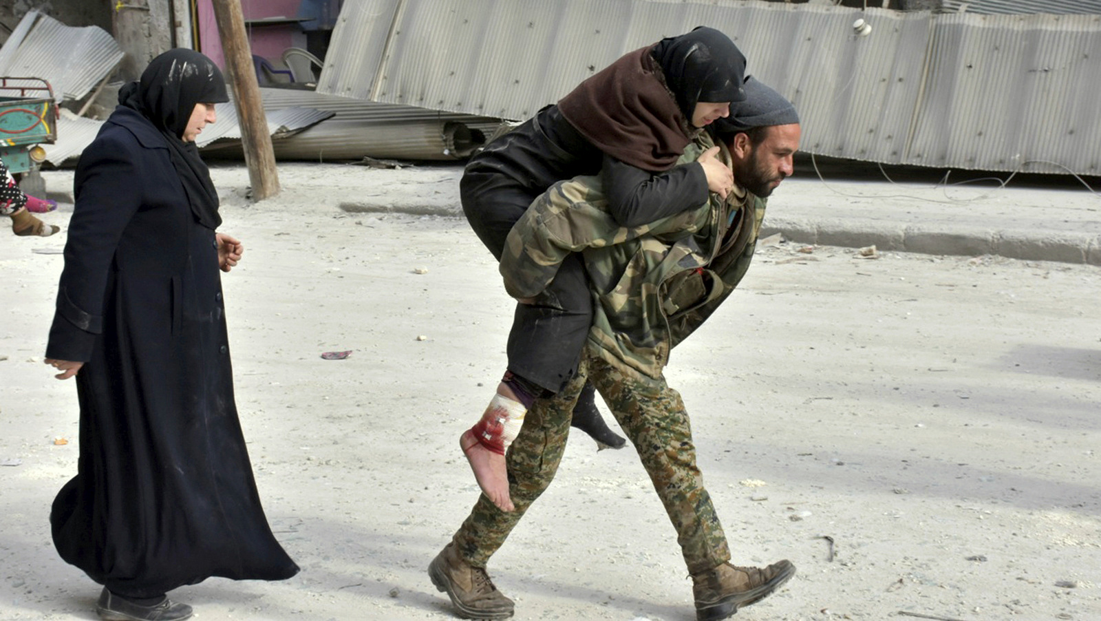 ASyrian soldier carries a wounded woman in eastern Aleppo, Syria, Monday, Dec. 12, 2016. Syria's military said Monday it has regained control of 98 percent of eastern Aleppo, as government forces close in the last remaining sliver of a rebel enclave packed with fighters as well as tens of thousands of civilians. (SANA via AP)