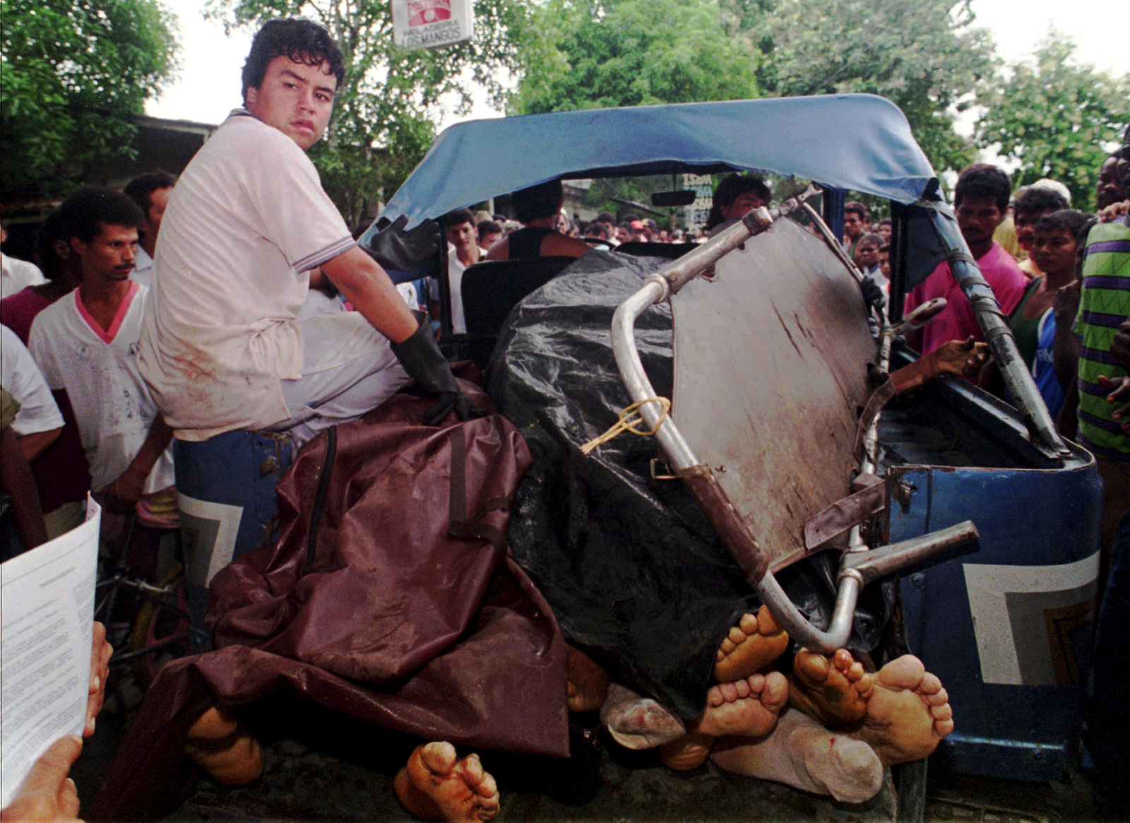 A man sits on the side of a jeep carrying the bodies of several of the at least 24 banana workers massacred by paramilitaries in the town of Apartado, Colombia, September, 1995. (AP Photo/Fernando Llano)