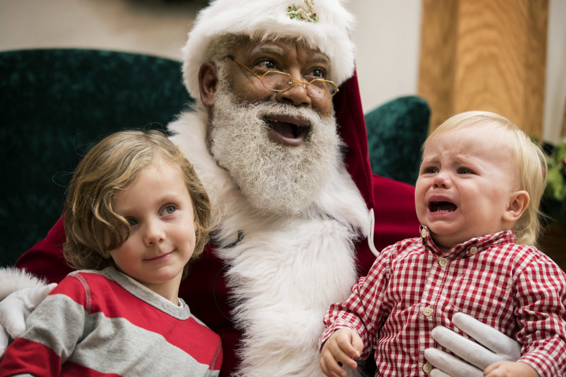 In this Thursday, Dec. 1, 2016 photo, Larry Jefferson, playing the role of Santa, smiles with Auden Good and his one-year-old brother Ezra of Ramsey while posing for photos at the Santa Experience at Mall of America in Bloomington, Minn. (Leila Navidi/Star Tribune via AP)