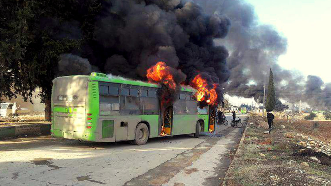 Smoke rises in green government buses, in Idlib province, Syria, Sunday, Dec. 18, 2016. Militants have burned at least five buses assigned to evacuate wounded and sick people from two villages in northern Syria. (SANA via AP)