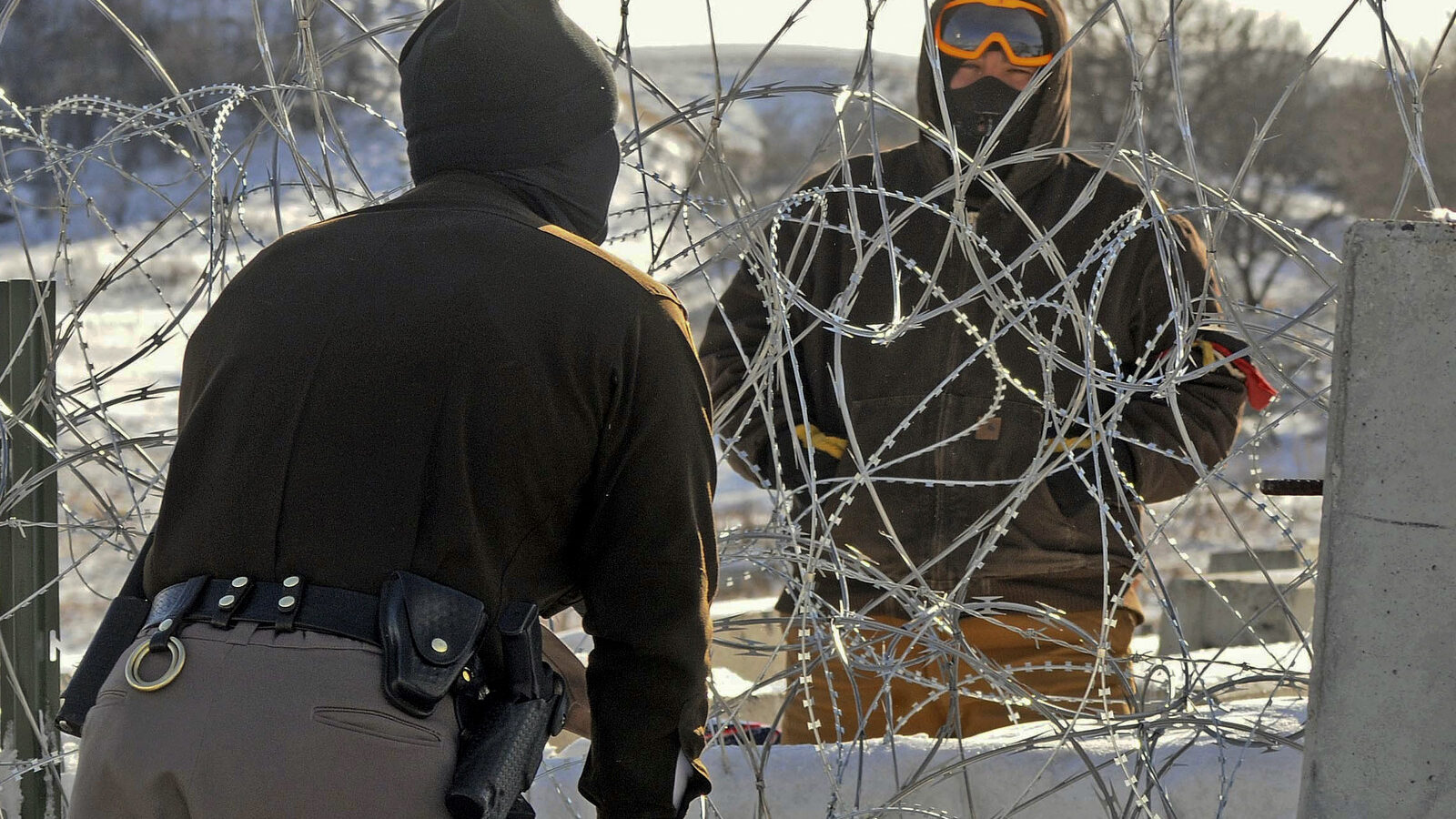 A law enforcement officer speaks to a protester against the Dakota Access Pipeline through a wall of razor wire on the Backwater Bridge over Cantapeta Creek on Thursday afternoon, Dec. 8, 2016. (Tom Stromme/The Bismarck Tribune via AP)