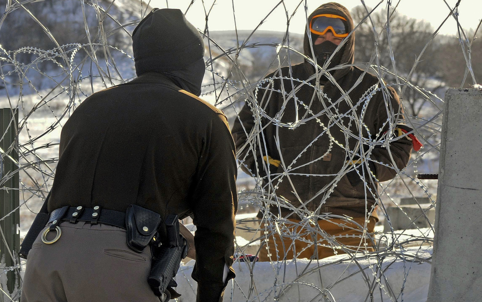 A law enforcement officer speaks to a protester against the Dakota Access Pipeline through a wall of razor wire on the Backwater Bridge over Cantapeta Creek on Thursday afternoon, Dec. 8, 2016. (Tom Stromme/The Bismarck Tribune via AP)