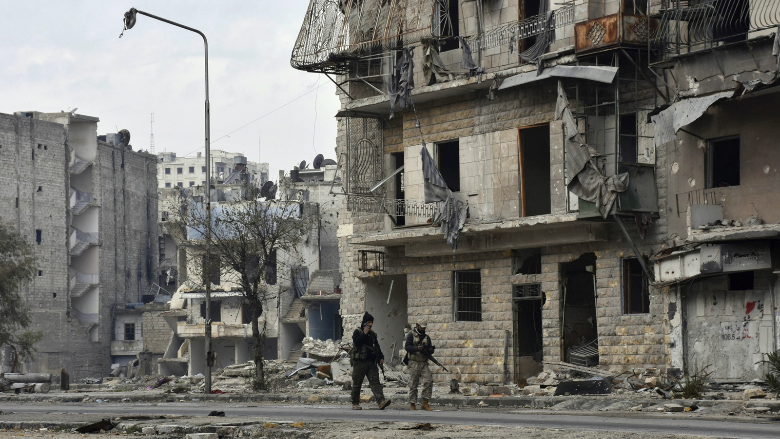 Syrian army soldiers march through the streets in the Ansari neighborhood, east Aleppo, Syria, Friday, Dec 23, 2016. (SANA via AP)