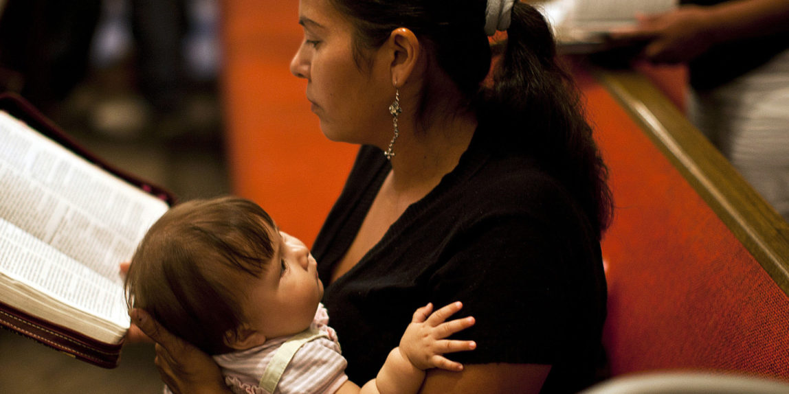 In this photo taken on Aug. 28, 2011, undocumented immigrant Maria Romero, holds her 8-month-old daughter Crista while she reads her Bible during a Disciples of Christ Sunday worship service. (AP/Nick Oza)