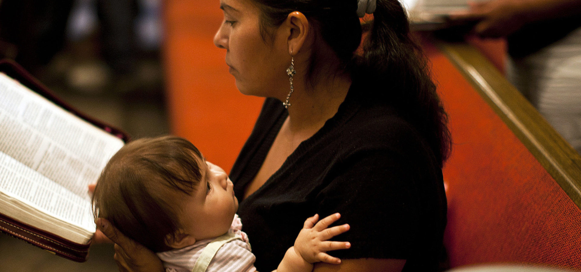 In this photo taken on Aug. 28, 2011, undocumented immigrant Maria Romero, holds her 8-month-old daughter Crista while she reads her Bible during a Disciples of Christ Sunday worship service. (AP/Nick Oza)