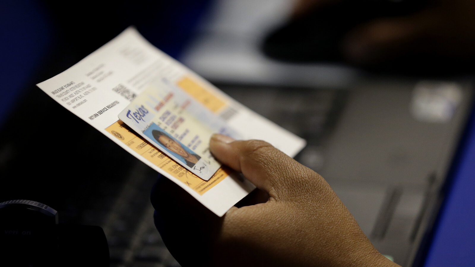 An election official checks a voter's photo identification at an early voting polling site in Austin, Texas. A federal appeals court is set to take a second look at a strict Texas voter ID law that was found to be unconstitutional last year. (AP/Eric Gay)