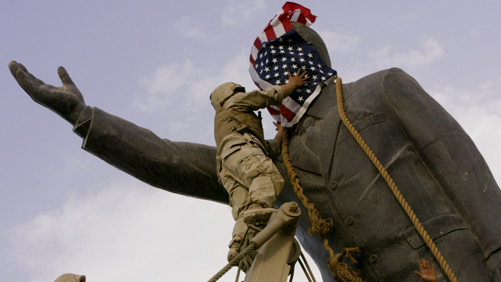 U.S. soldiers cover the face of a statue of Saddam Hussein with an American flag before toppling the statue in downtown in Baghdad, Iraq. (AP/Jerome Delay)