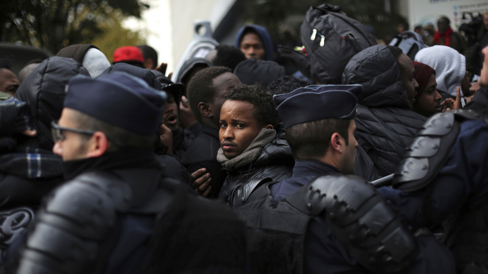 Migrants are pushed back by police officers as they wait to board buses to temporary shelters in Paris, Friday, Nov. 4, 2016. (AP/Thibault Camus)