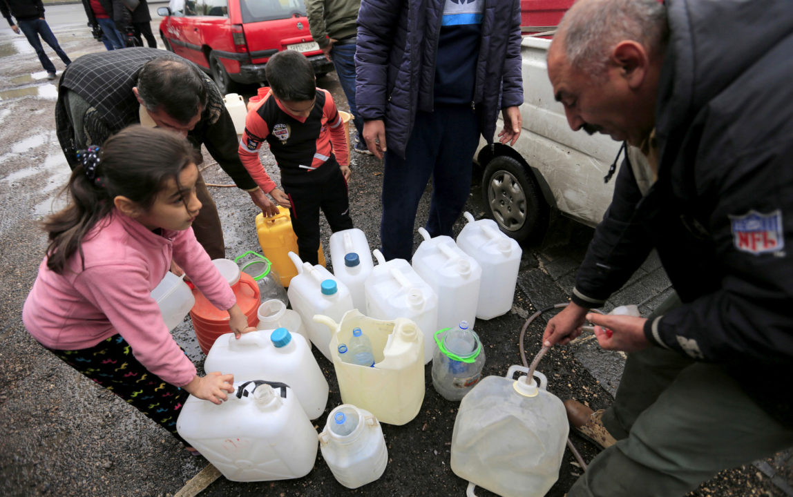 People fill plastic containers with water from a tap water in Damascus, Syria, Monday, Jan. 16, 2017. Water cut-offs have been almost continuous since Dec. 22, in the worst water crisis known to Damascus residents. (AP/Hassan Ammar)