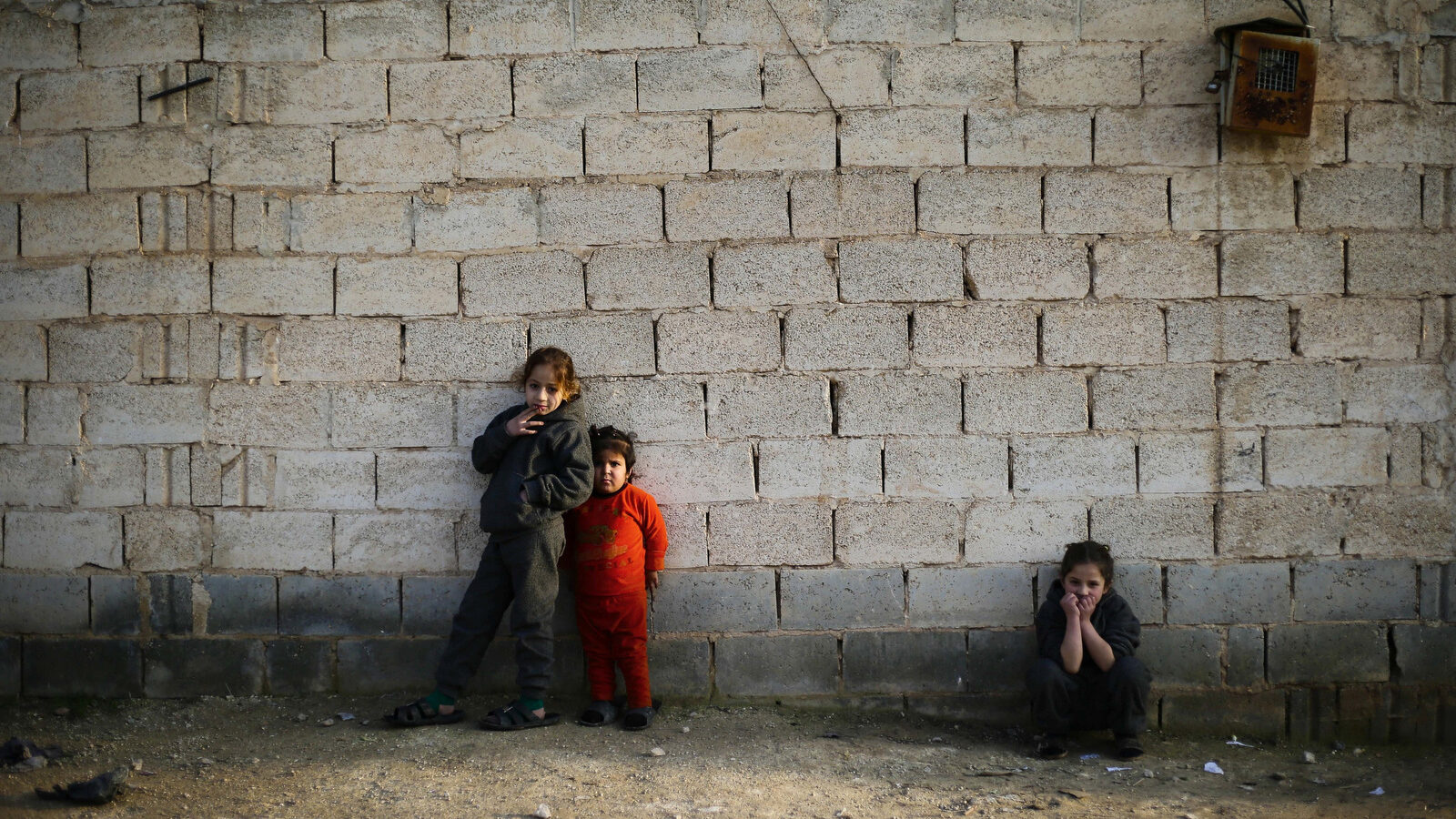 In this Wednesday, Jan. 18, 2017 photo, Syrian girls who fled from the village of Deir Hafer with their family watch their brothers playing in the town of Safira, just south of Aleppo, Syria, Wednesday, Jan. 18, 2017. As Islamic State-held areas in northern Syria come increasingly under attack by an assortment of groups, thousands of civilians have been risking their lives to make the perilous journey out, paying smugglers to escape the shelling and the extremist group's terror, many of them opting to go to government-controlled territory. (AP Photo/Hassan Ammar)