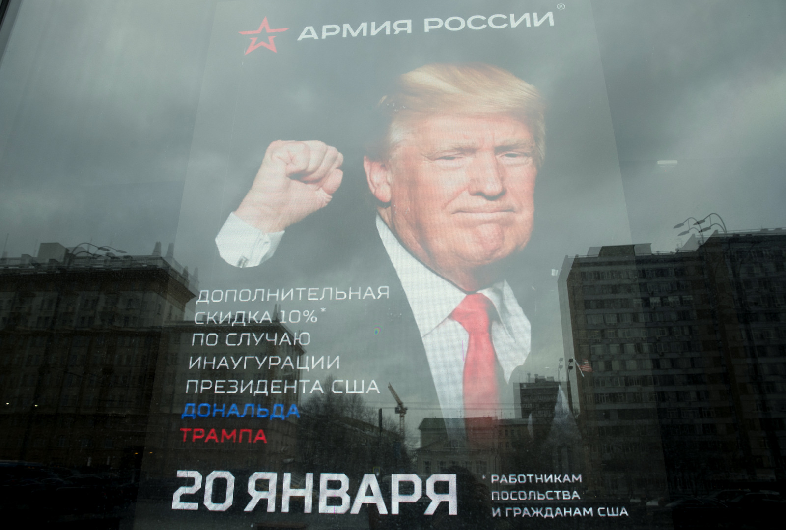 The U.S. Embassy building is reflected in a window of a Russian military outerwear shop "Armia Rossii" (Russian Army) displaying a poster of Donald Trump, in downtown Moscow, Russia, Friday, Jan. 20, 2017, hours ahead of Donald Trump being sworn in as president of the United States, The poster reads: "10 percent discount to the embassy employees and US citizens on the Inauguration Day". (AP/Pavel Golovkin)