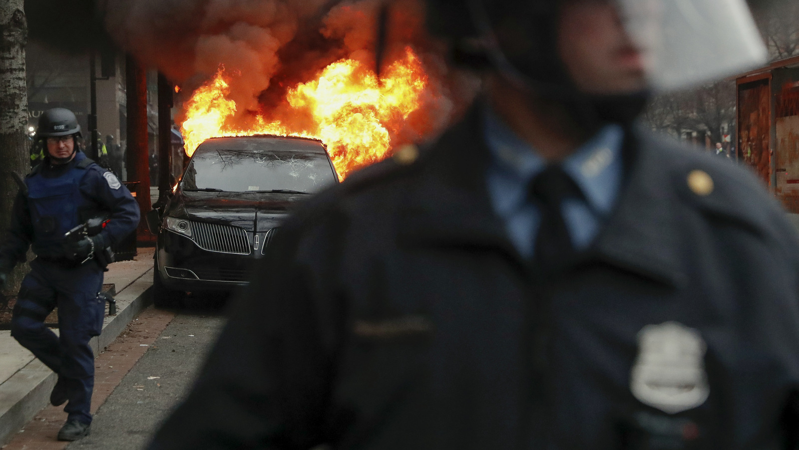 A parked limousine burns as riot police clear the street during a demonstration after the inauguration of President Donald Trump, Friday, Jan. 20, 2017, in downtown Washington. (AP/John Minchillo)