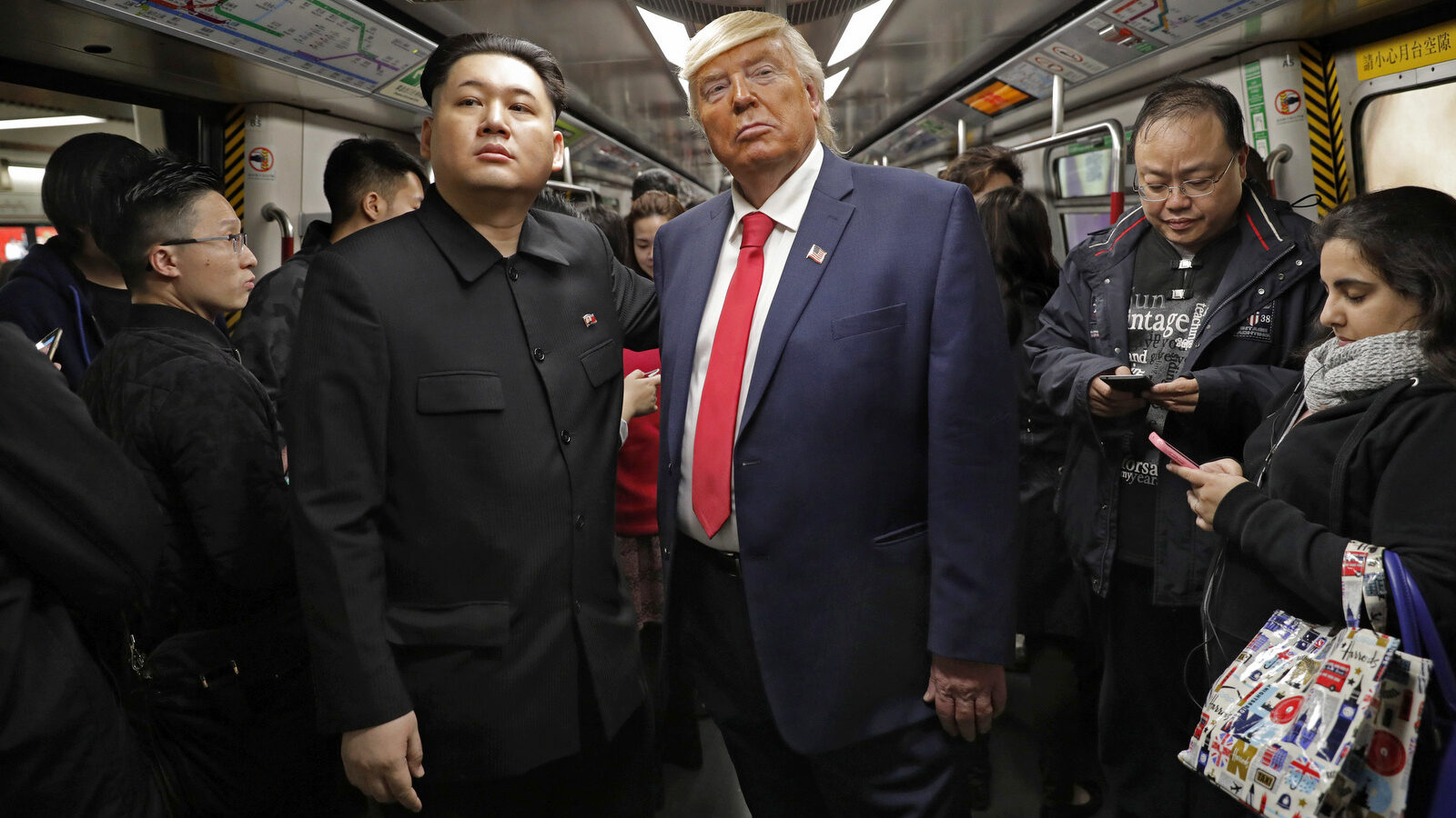 Kim Jong Un and Donald Trump impersonators, Howard, left, and Dennis, right, (who only give their first name) stand side by side on a train to promote a music video they created in Hong Kong, Wednesday, Jan. 25, 2017. (AP Photo/Vincent Yu)