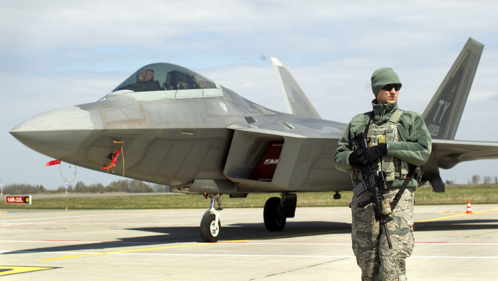 A U.S. military policeman stands in front of a U.S. Air Force F-22 Raptor fighter jet at the Siauliai airbase, some 230 km (144 miles) east of the capital Vilnius, Lithuania, Wednesday, April 27, 2016. (AP/Mindaugas Kulbis)