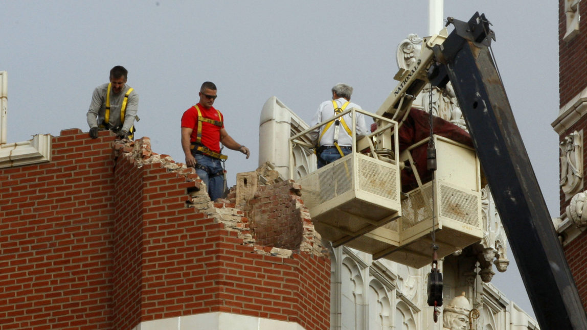 Maintenance workers inspect the damage to one of the spires on Benedictine Hall at St. Gregory's University following an earthquake in Shawnee, Okla, Nov. 6, 2011. (AP/Sue Ogrocki)