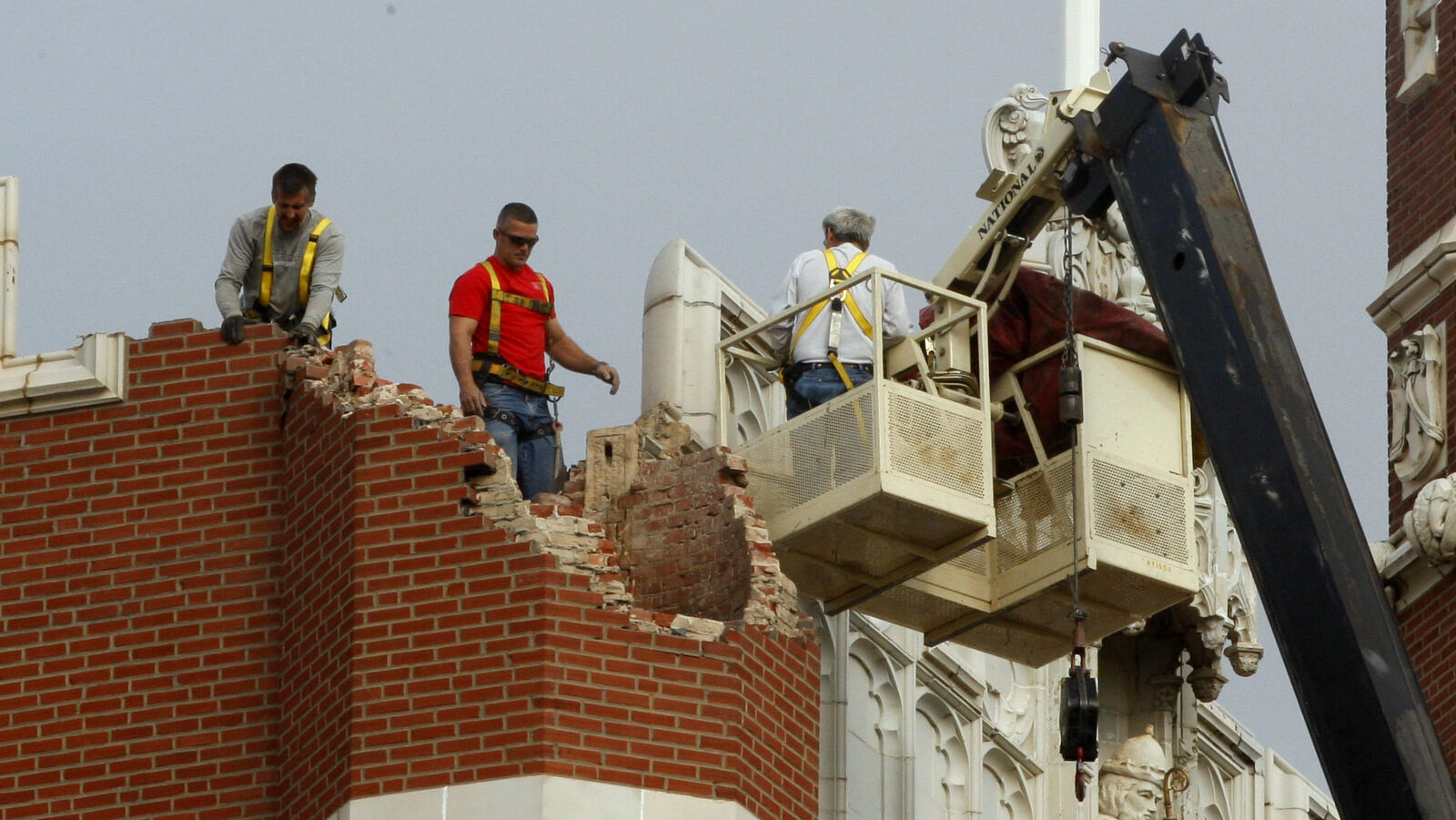 Maintenance workers inspect the damage to one of the spires on Benedictine Hall at St. Gregory's University following an earthquake in Shawnee, Okla, Nov. 6, 2011. (AP/Sue Ogrocki)